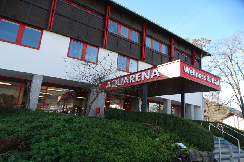 Restaurant Naturtalent Das Gebäude hat ein rotes Schild mit der Aufschrift "AQUARENA Wellness & Bad". Es ist von einer grünen Landschaft umgeben.
