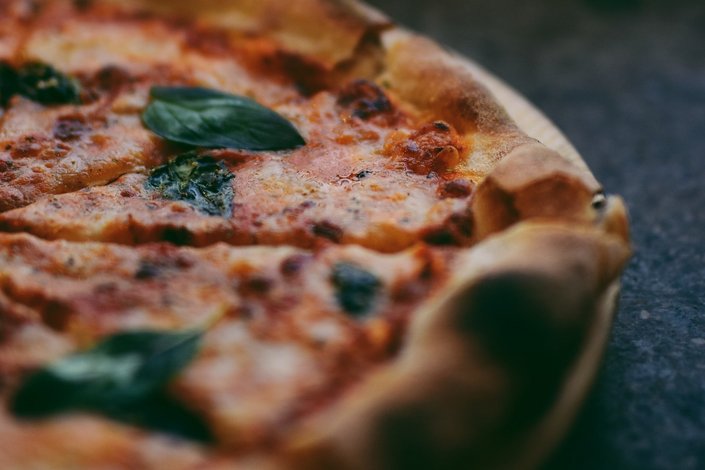 A Pizza with basil leaves on top