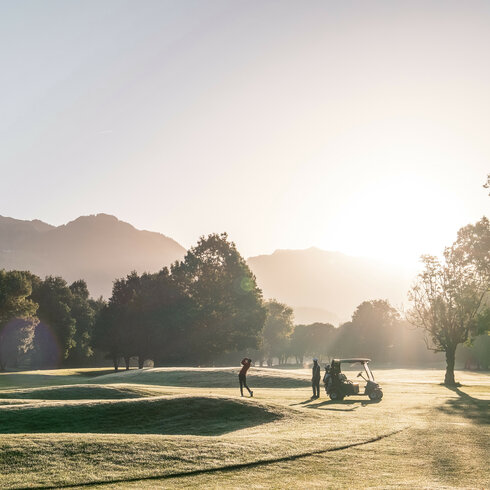 Golfer spielen am Morgen auf dem Golfplatz Kitzbühel-Schwarzsee-Reith, umgeben von Bergen.
