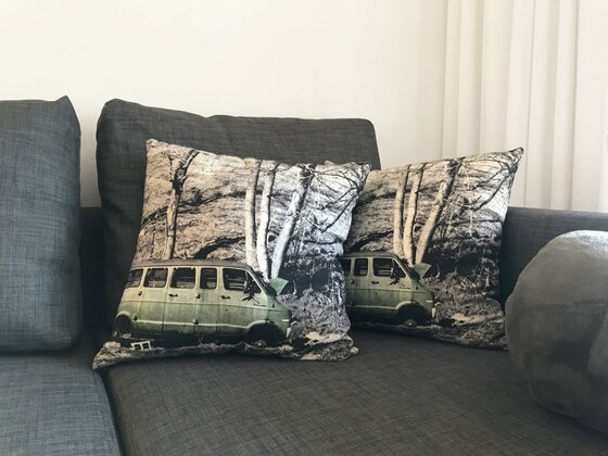 Zwei Dekokissen mit einem Van-Motiv auf einem grauen Sofa.