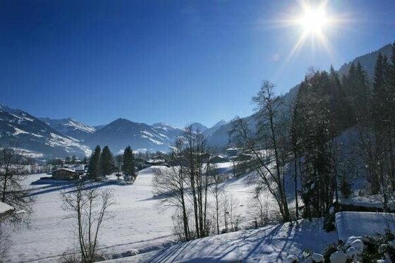 Winterlicher Ausblick Schatz Verschneites Tal mit Dorf und Bergen unter blauem Himmel bei Sonnenschein.