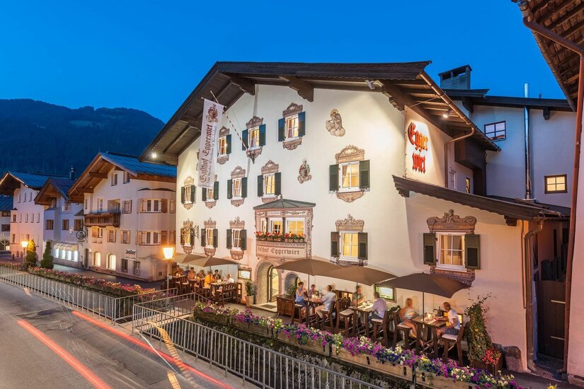 Gasthof Eggerwirt Kitzbühel Beleuchteter Gasthof Eggerwirt in Kitzbühel bei Dämmerung mit Gästen auf der Außenterrasse.