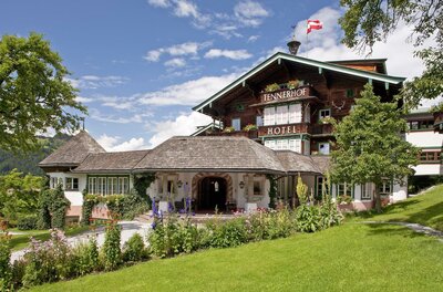 Hotel Tennerhof Außenansicht Außenansicht des Hotel Tennerhof mit Holzfassade, Blumengarten und österreichischer Flagge unter blauem Himmel.