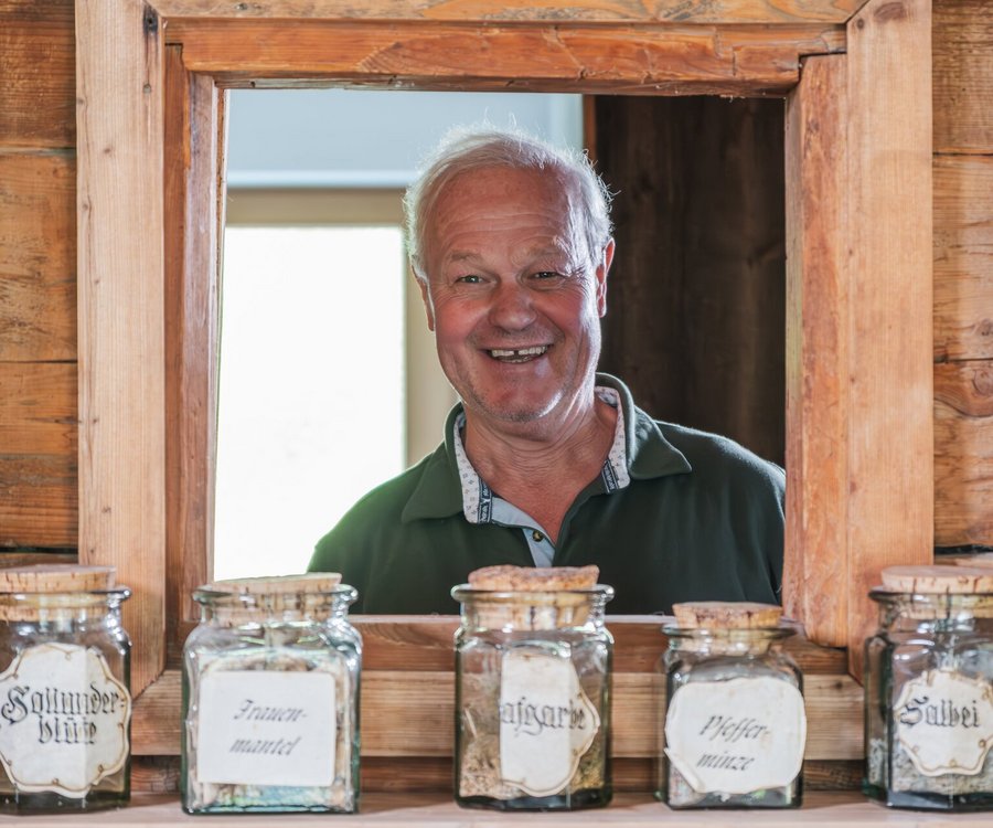 A man smiling through a window behind selfmade tea 