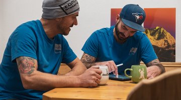 Zwei Männer schreiben bei einem Kaffee ihre Ideen auf