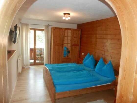 Schlafzimmer mit Doppelbett, blauer Bettwäsche, Holzschrank und holzgetäfelter Wand.