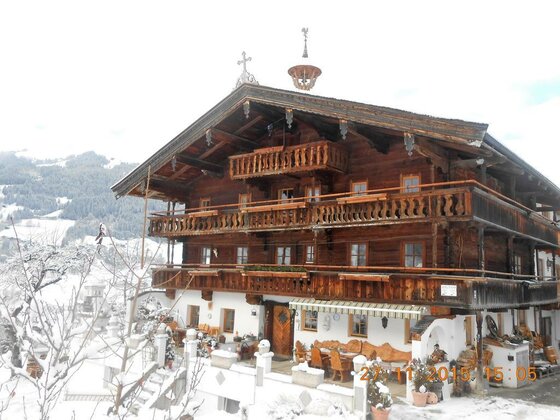 Mehrstöckiges Holzhaus mit Balkonen in verschneiter Berglandschaft.
