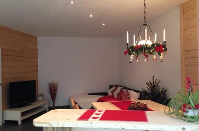 Wohnbereich im Haus Haas Wohnbereich mit Holztisch, Sofa, Fernseher und weihnachtlicher Dekoration.