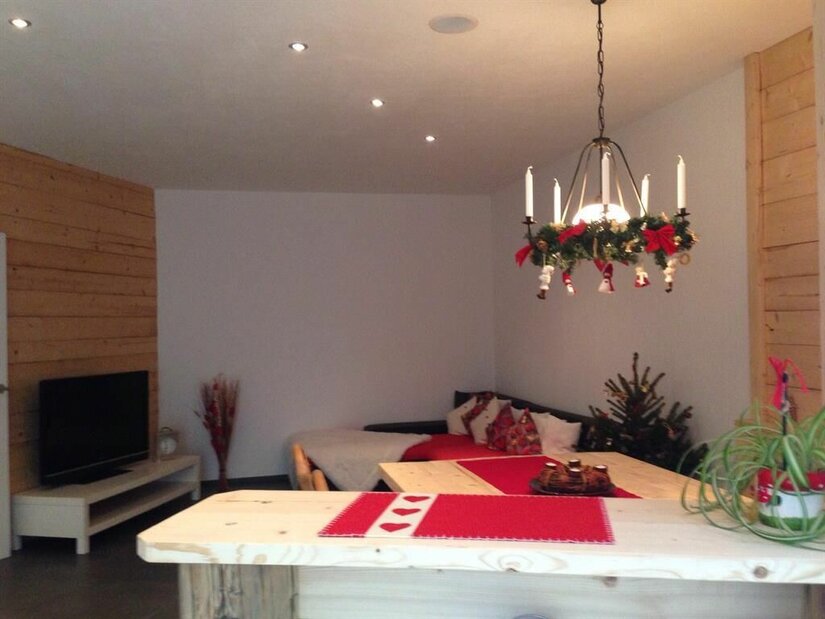 Wohnbereich im Haus Haas Wohnbereich mit Holztisch, Sofa, Fernseher und weihnachtlicher Dekoration.