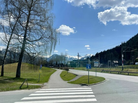 Radweg an der Kitzbüheler Runde Zebrastreifen und asphaltierter Radweg neben einer Straße mit Blick auf schneebedeckte Berge.