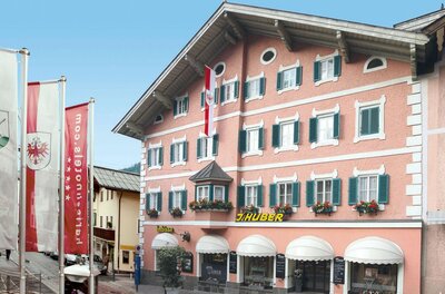 Metzgerei Huber Fassade Mehrstöckiges rosa Gebäude mit grünen Fensterläden und dem Schriftzug J. Huber.
