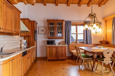 Küche und Essbereich im Chalet Rustikale Holzküche mit angrenzender Essecke und Holzbalkendecke.