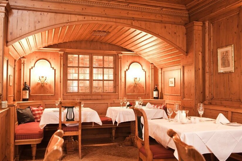 Restaurant Das Reisch Rustikale Gaststube mit Holzvertäfelung, eingedeckten Tischen und gepolsterten Eckbänken.