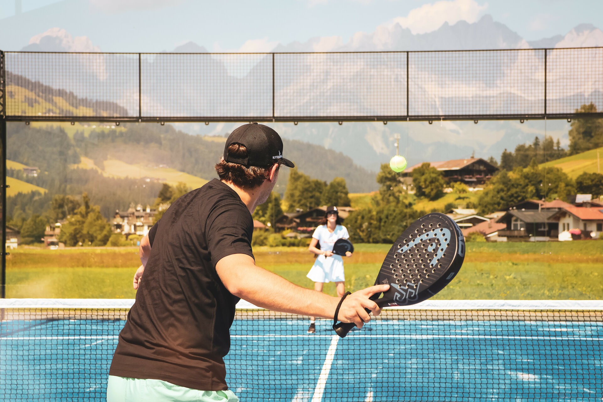 Two people are playing padel tennis against a stunning backdrop