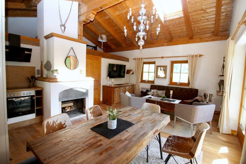 Wohn- Essbereich OG Rustikaler Wohn- und Essbereich mit Holztisch, Kamin, Sofa und sichtbarem Dachstuhl.