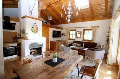 Wohn- Essbereich OG Rustikaler Wohn- und Essbereich mit Holztisch, Kamin, Sofa und sichtbarem Dachstuhl.
