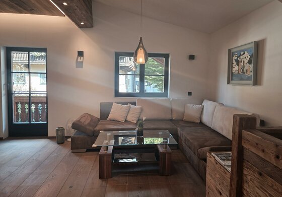 Wohnbereich Resi's Kitz Lodge Modernes Wohnzimmer mit großem Ecksofa, Glastisch und Holzboden.