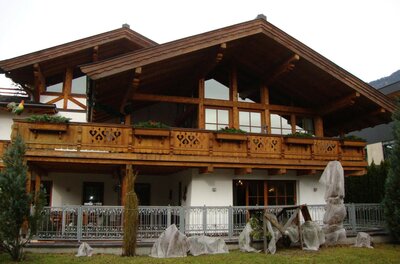 Haus Andreas in Kitzbühel Alpines Wohnhaus aus Holz und weißem Putz mit großem Balkon und Garten.