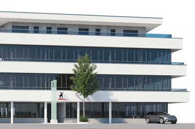 Kitzbüheler Anzeiger Ein modernes Bürogebäude mit großen Fensterfronten und einem klaren Design. Vor dem Gebäude steht ein Baum und ein Auto parkt auf der Straße.