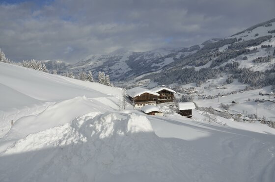 Winterliche Berglandschaft mit Holzhäusern Verschneite Holzhäuser in einer alpinen Winterlandschaft mit Bergen im Hintergrund.