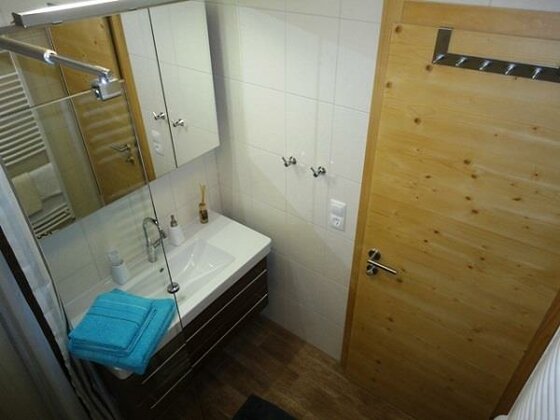 Badezimmer der Genneralm Modernes Badezimmer mit weißem Waschbecken, Spiegelschrank und Holztür.