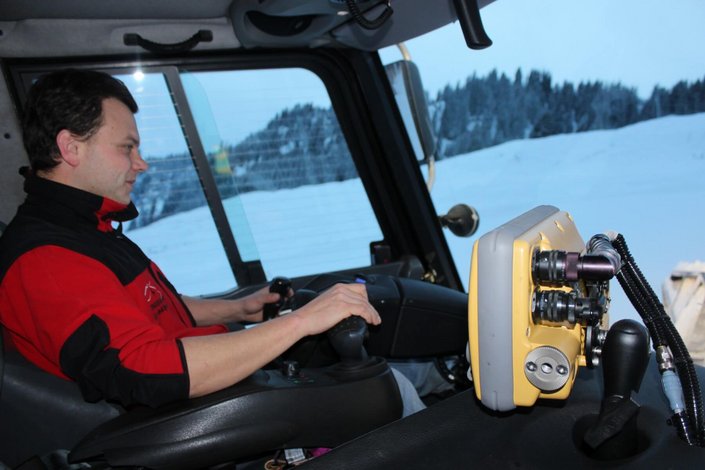 Mann fährt Pistenraupe