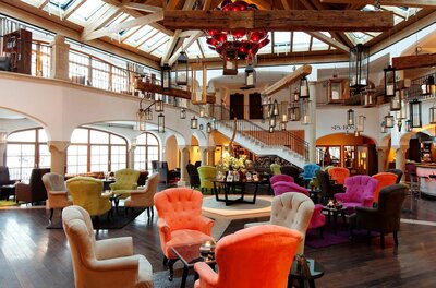 Große Hotellobby mit bunten Sesseln, Holzbalkendecke und zahlreichen hängenden Laternen.