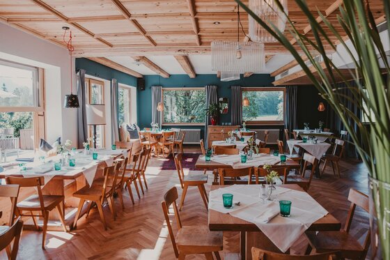 Restaurant im Hotel Seebichl Moderner Gastraum mit Holztischen, blauen Wänden und Parkettboden.