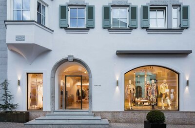 Boutique Helmut Eder Damen Außenansicht einer Modeboutique mit Rundbogen-Eingang und Schaufenstern in einem historischen Gebäude.