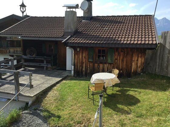 Rustikale Holzhütte mit Terrasse, Rasenfläche und einer Sitzgruppe im Freien.