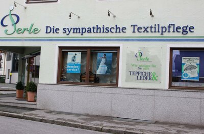 Perle Ein Geschäft mit der Beschriftung „Perle - Die sympathische Textilpflege“. Es bietet Dienstleistungen für Textilien und Leder an.