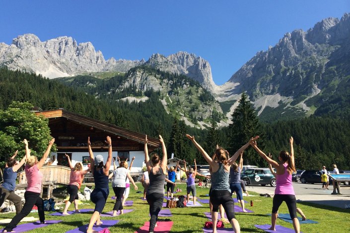 Yogagruppe vor Berglandschaft