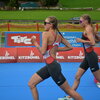Mit Sonnenbrillen und sportlicher Kleidung sprinten zwei Frauen über die Laufstrecke eines Triathlons in Kitzbühel.