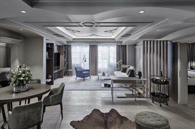 Modern eingerichteter Wohnbereich einer Hotelsuite mit Esstisch, Sofa und Sessel.