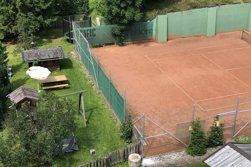 Tennisplatz Hechenmoos Ein Tennis-Sandplatz neben einer Liegewiese mit Spielplatz und Trampolin.