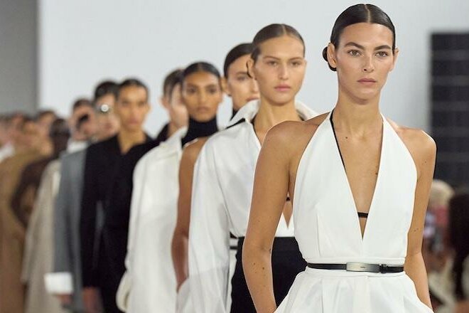 Max Mara Modenschau Mehrere Models laufen hintereinander in weißer und schwarzer Kleidung über einen Laufsteg.