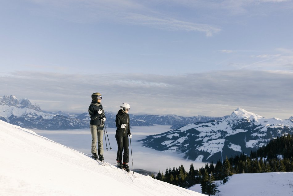 Ein Paar steht am Berg mit Skien in der verschneiten Landschaft