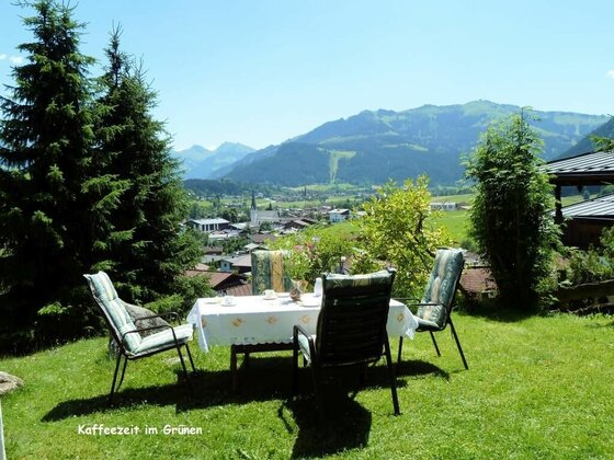Kaffeezeit im Garten Gartentisch mit vier Stühlen auf einer Wiese vor Bergpanorama.
