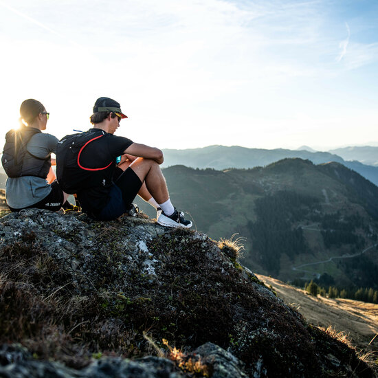 Zwei Freunde genießen die Ruhe der Natur, während sie auf einem Felsen sitzen und die beeindruckende Berglandschaft betrachten.