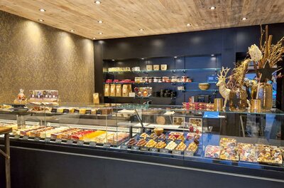 Verkaufstheke einer Konditorei mit verschiedenen Kuchen, Torten und Pralinen hinter Glas.