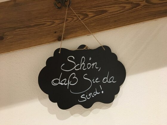 Willkommensgruß auf Kreidetafel Schwarze Kreidetafel in Wolkenform mit dem handgeschriebenen Text: Schön, daß Sie da sind!