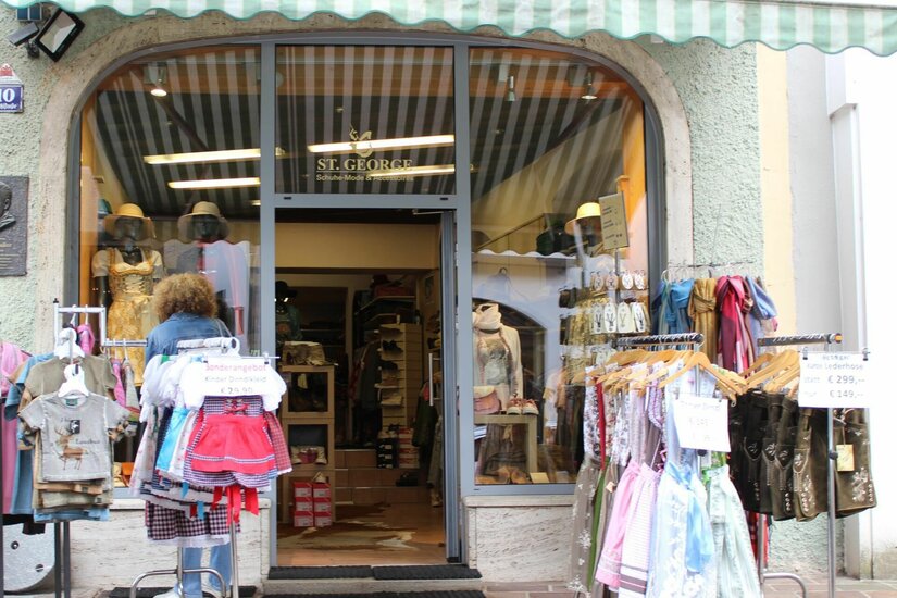 Modegeschäft St. George Eingangsbereich eines Modegeschäfts mit Trachtenmode auf Kleiderständern im Außenbereich.
