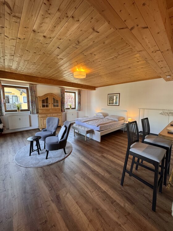City-apart Stadl Innenansicht Modernes Zimmer mit Holzdecke, Doppelbett, Sitzecke und Laminatboden.