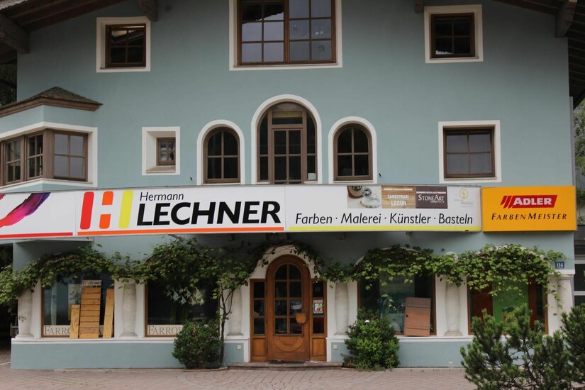 Fassade des Geschäfts Hermann Lechner für Farben und Künstlerbedarf mit hellblauer Wand und Holztür.