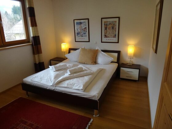 Schlafzimmer im Penthouse Retreat Doppelbett mit weißer Bettwäsche, zwei Nachttischen mit Lampen und zwei Bildern an der Wand.