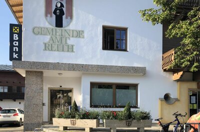 Außenansicht des Gemeindeamts Reith mit Wappen und Schriftzug an der weißen Fassade.