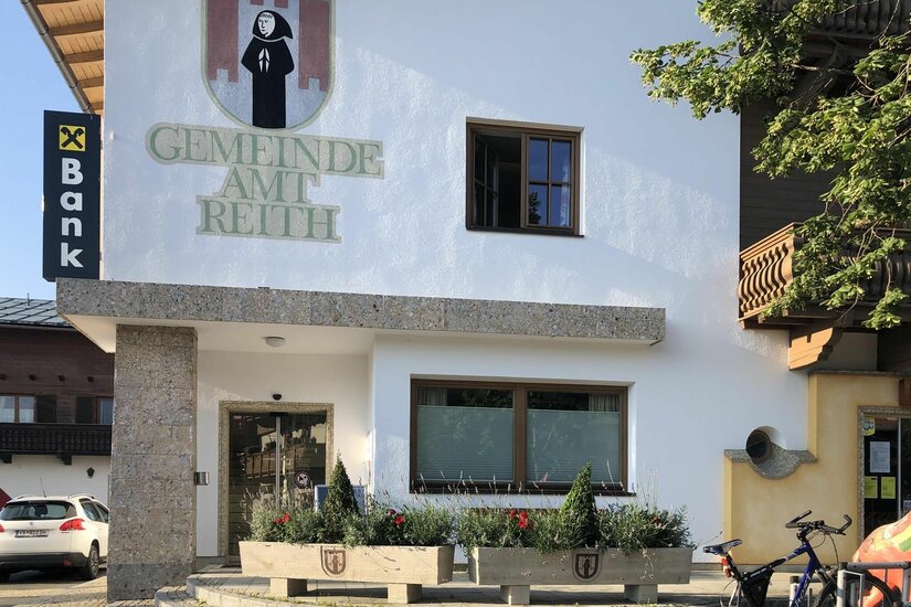 Außenansicht des Gemeindeamts Reith mit Wappen und Schriftzug an der weißen Fassade.