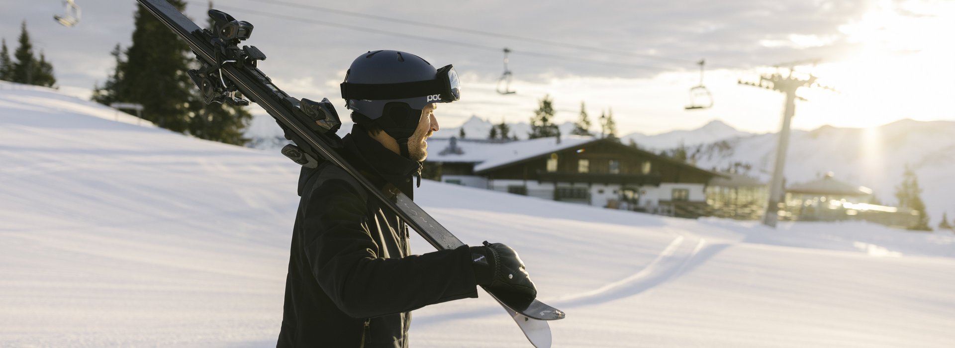 Mann trägt seine Ski in Richtung Piste