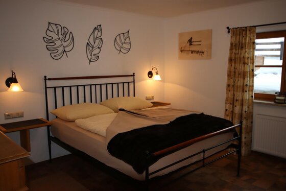Schlafzimmer 1 Doppelbett mit schwarzem Metallrahmen, Wandlampen und Blatt-Dekoration in einem Schlafzimmer.
