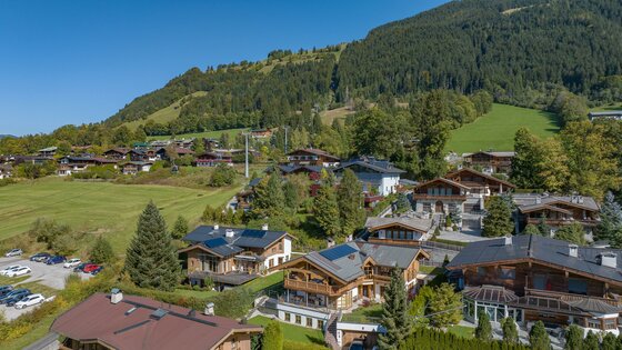 Chalet Kitzbühelblick mit Hornbahn Blick auf Chalets in Hanglage mit der Hornbahn im Hintergrund vor bewaldeten Bergen.